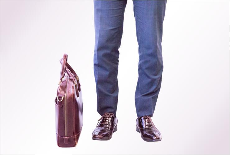 自立型の茶色いバッグと男性の足元